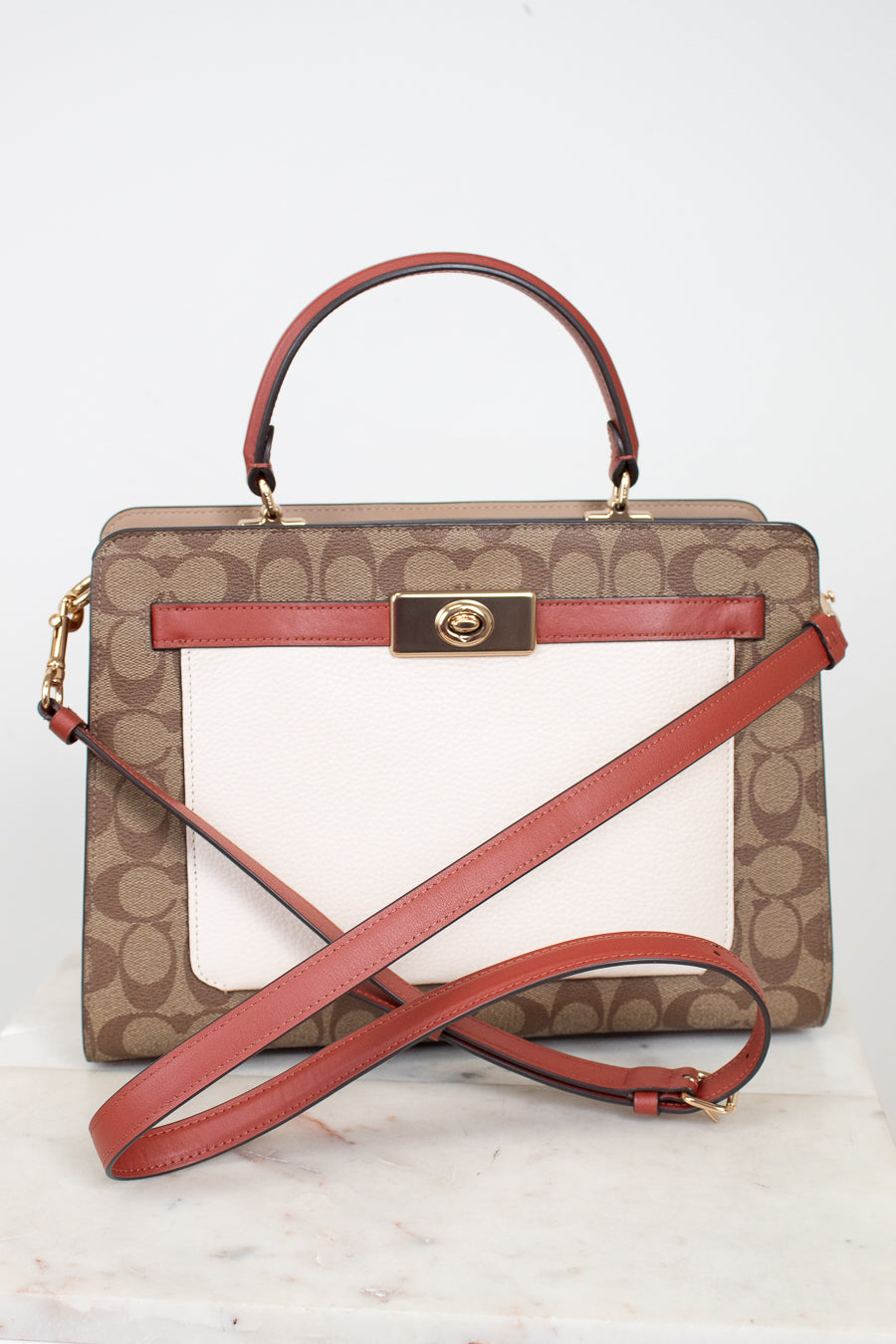 Coach handbag with brown pattern and red accents on a white background
