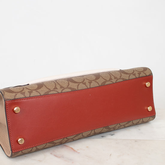 Bottom view of red and beige handbag with gold hardware on a white surface