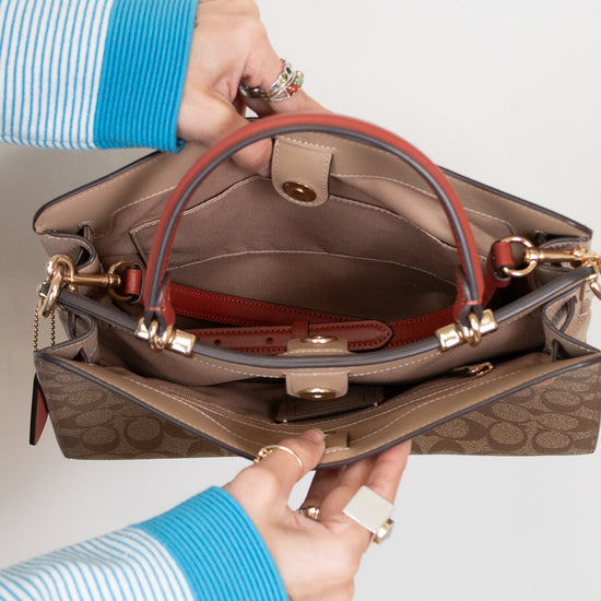 Person holding a brown handbag with a visible brand logo on a light gray background