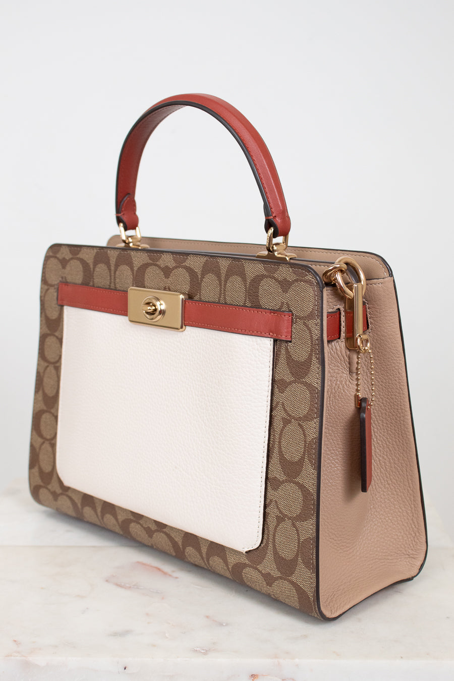 Designer handbag with brown and red accents on a light background
