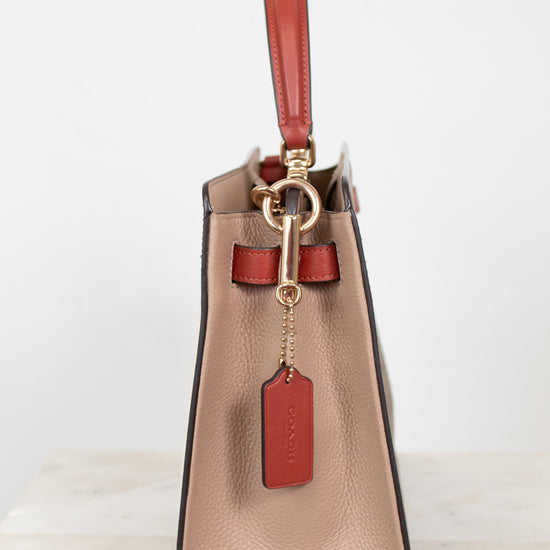 Beige handbag with red strap and tag on a white background