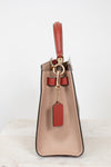 Beige handbag with red strap and tag on a white background