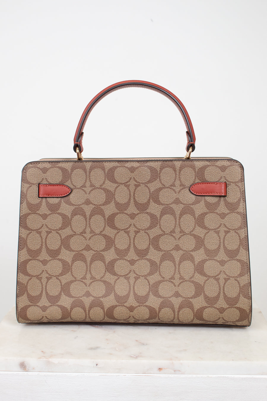 Beige handbag with red accents on a white background