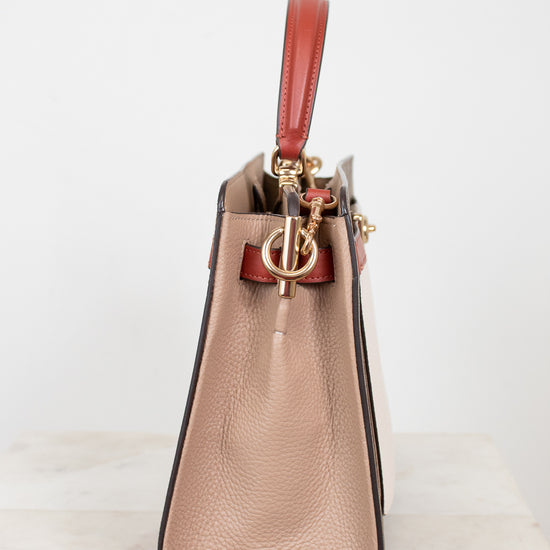 Beige handbag with a red handle on a white background