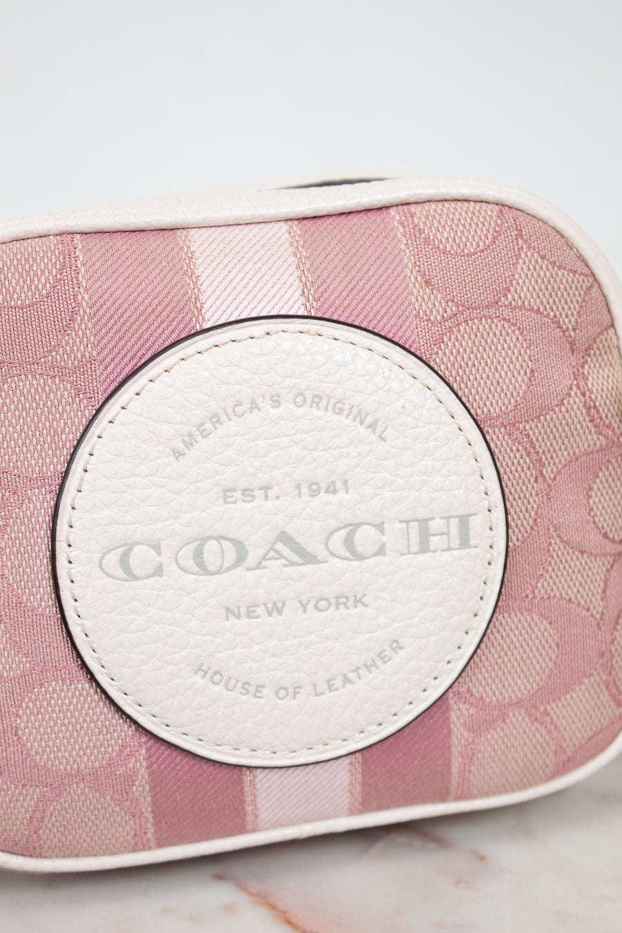 Coach bag with pink pattern and white logo on a marble surface