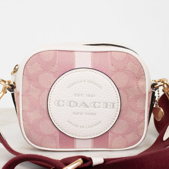 Coach handbag with pink plaid pattern and gold accents on a light background