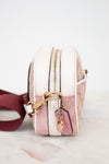 Pink and white handbag with gold zipper and accents on a light background