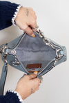 Person holding open light blue bag with silver chain details