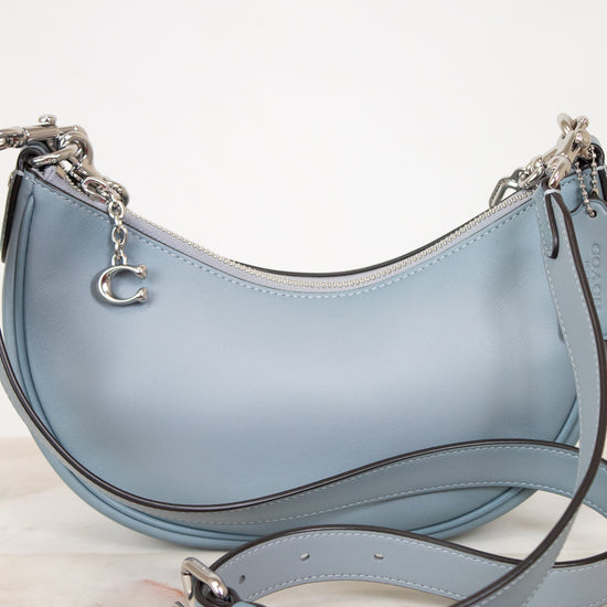 Light blue handbag with a matching strap on a light background
