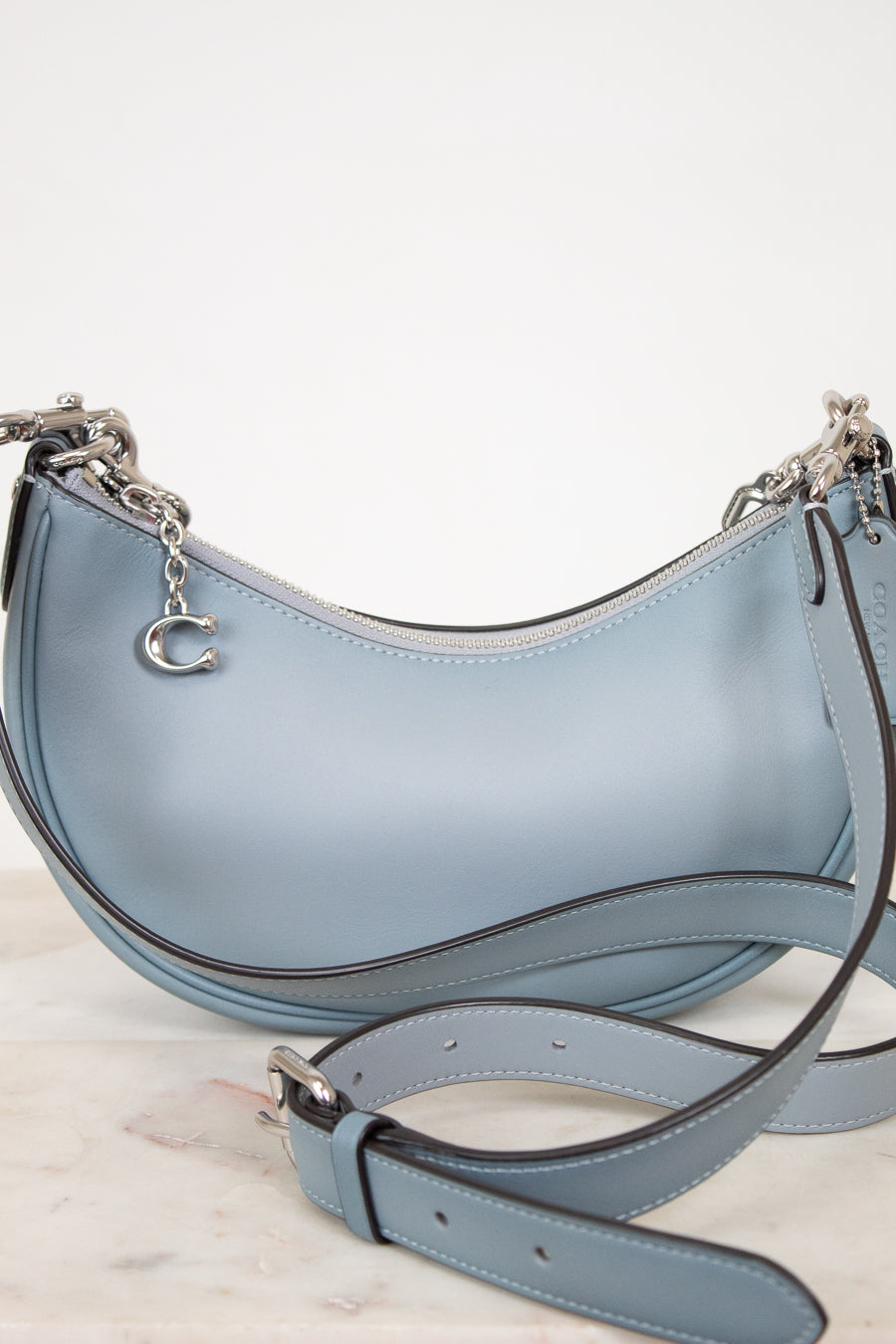 Light blue handbag with a matching strap on a light background