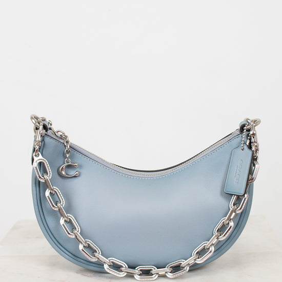 Light blue handbag with silver chain detail on a white background