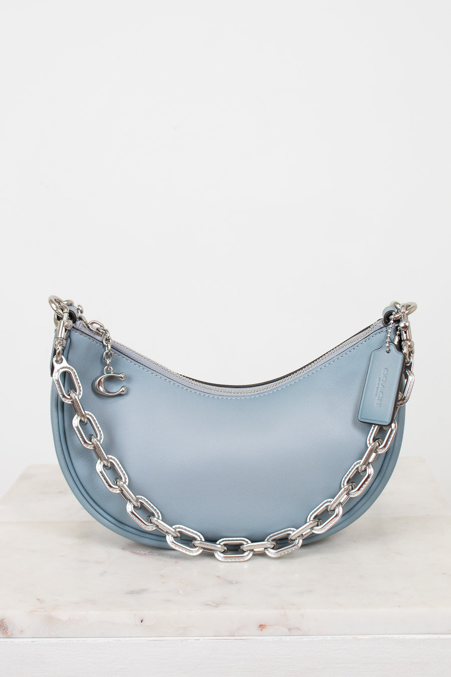 Light blue handbag with silver chain detail on a white background