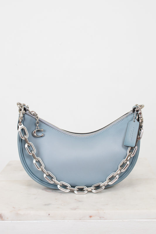 Light blue handbag with silver chain detail on a white background