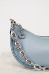 Light blue handbag with a silver chain detail on a white background