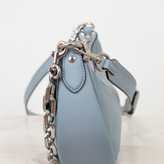 Light blue handbag with a chain detail on a white background