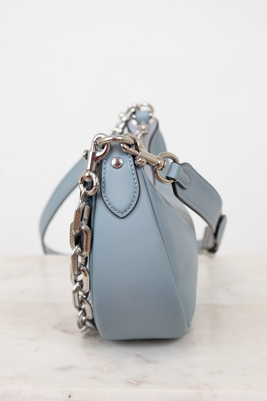 Light blue handbag with a chain detail on a white background