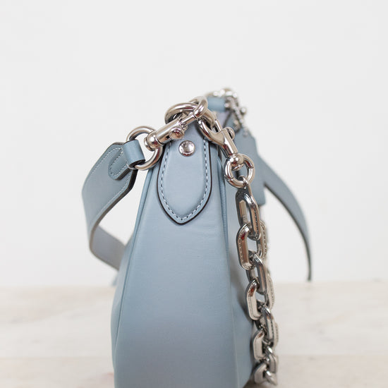 Light blue handbag with a chain detail on a light background