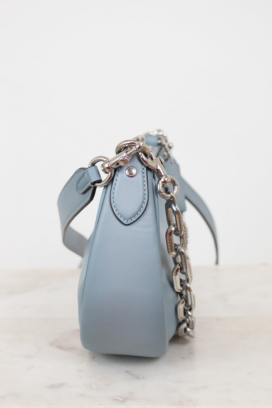 Light blue handbag with a chain detail on a light background