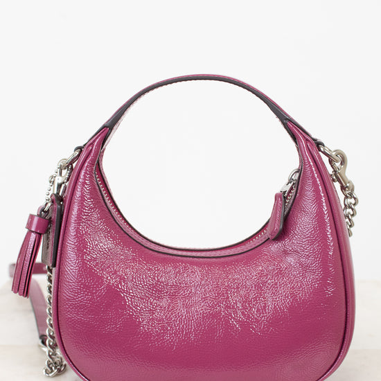A pink pebbled leather hobo handbag with silver chain strap details, displayed on a light marble surface against a white background.