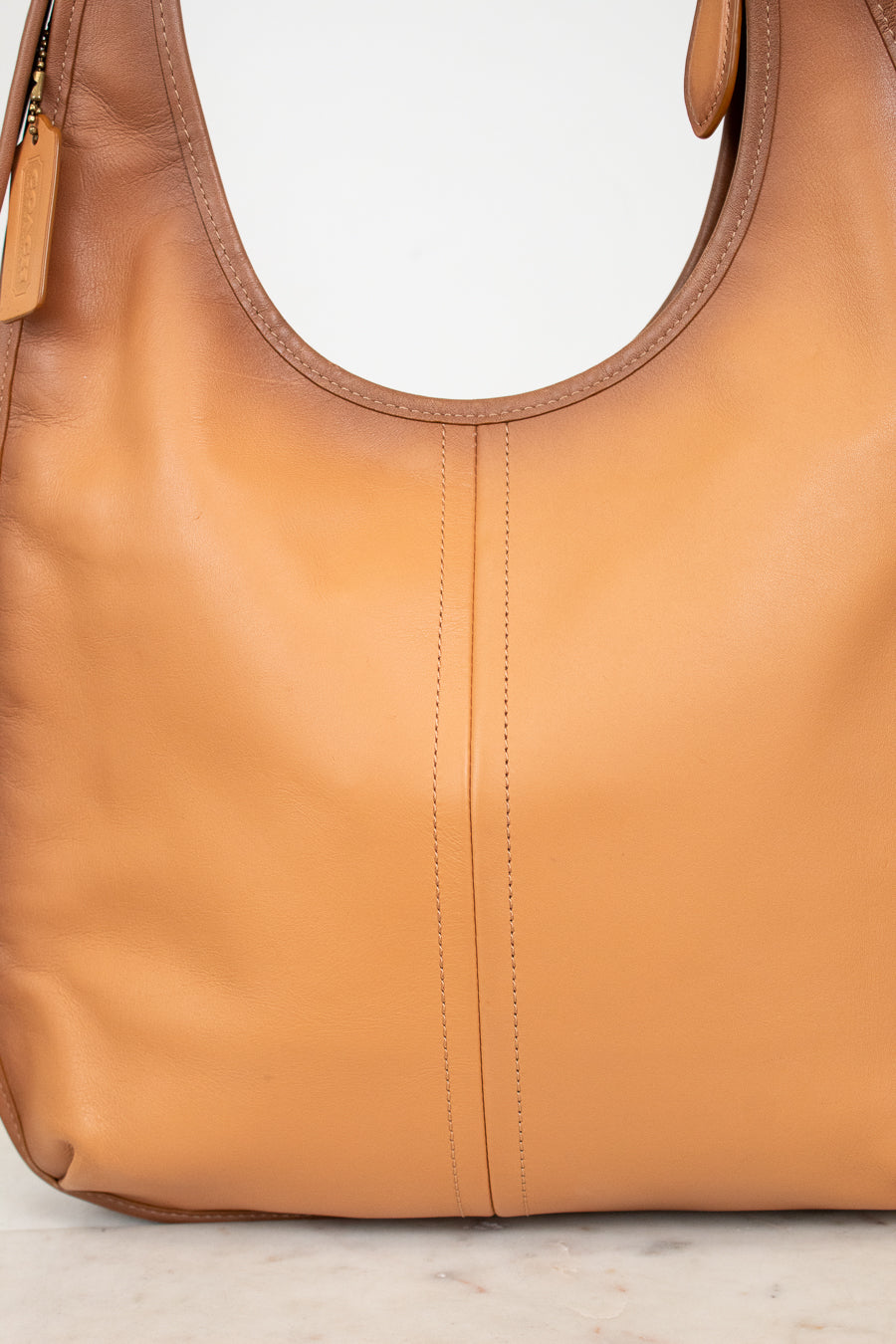 Tan leather handbag on a light gray background