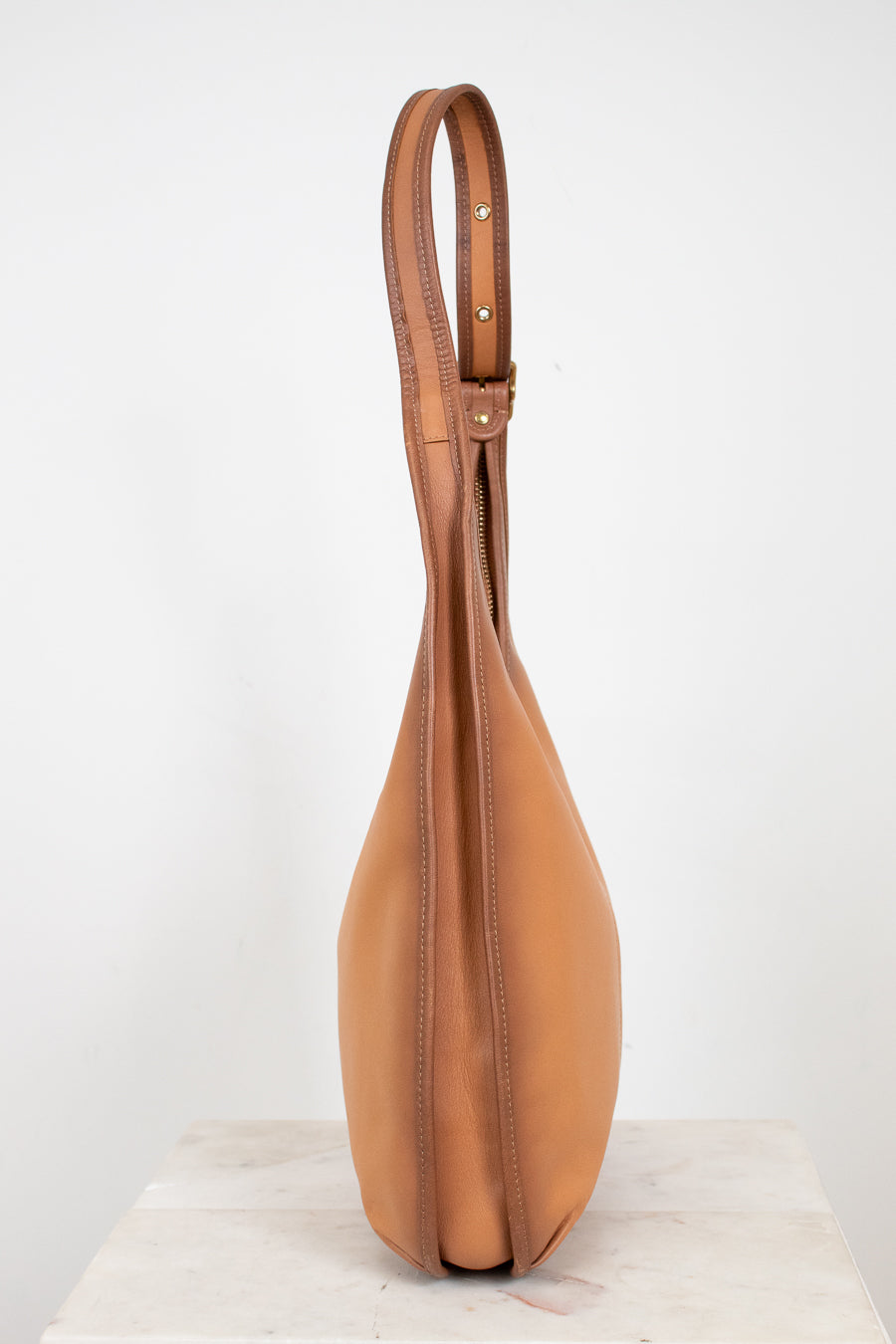 Tan leather handbag with a strap on a white background