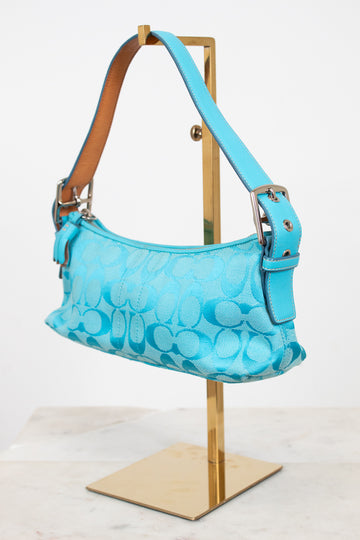 Blue handbag with a pattern on a wooden stand against a white background