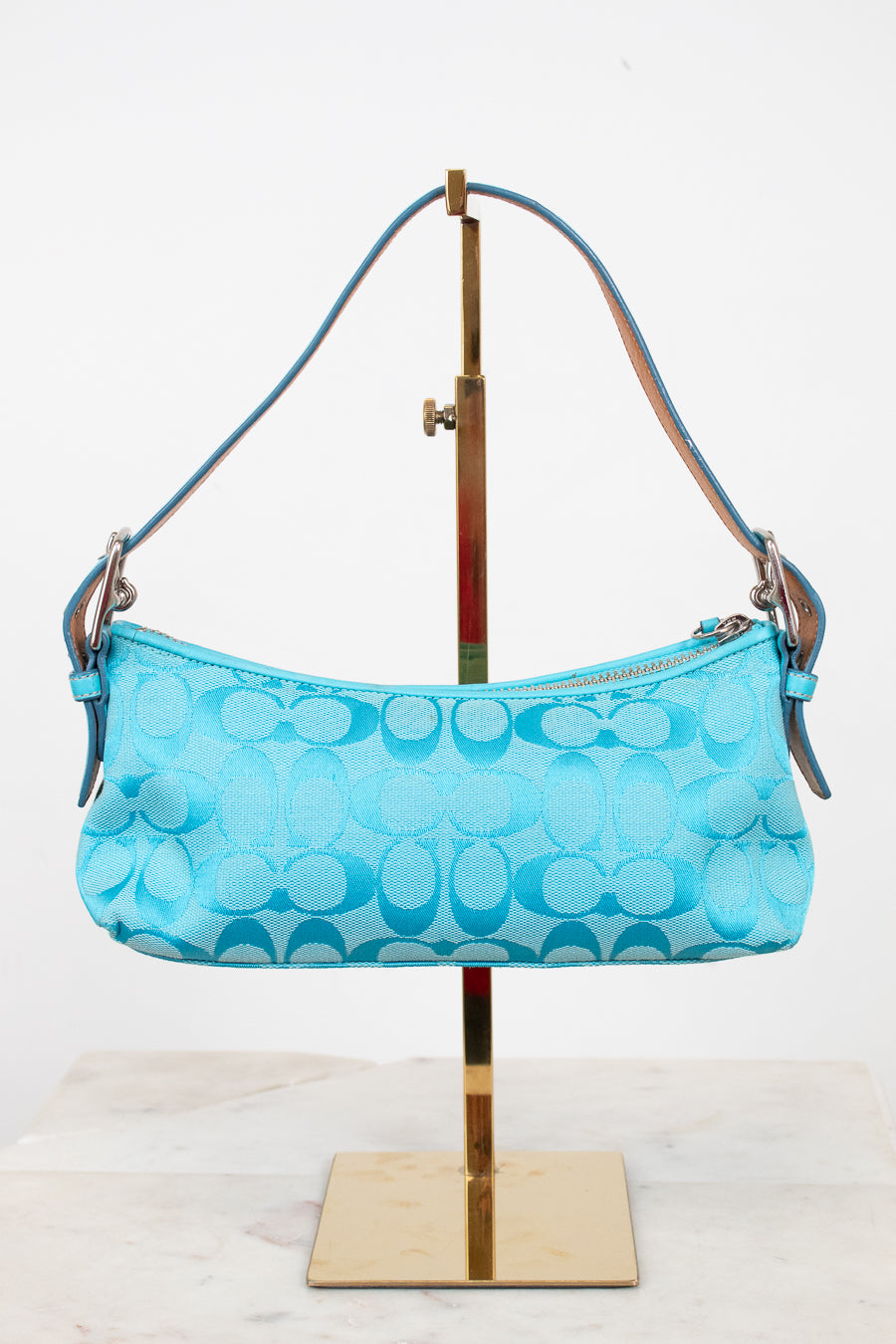 Blue handbag on a stand against a white background