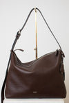 A dark brown leather hobo shoulder bag with a top zipper and a long shoulder strap, displayed on a white surface against a light gray background.