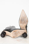 A pair of black leather high-heeled boots with sculptural, wheel-like beige and brown platform soles, photographed on a white background.
