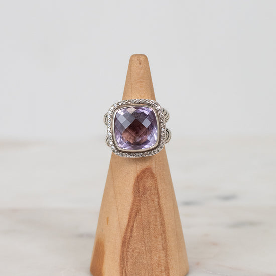 Ring with a purple gemstone on a wooden stand against a light background