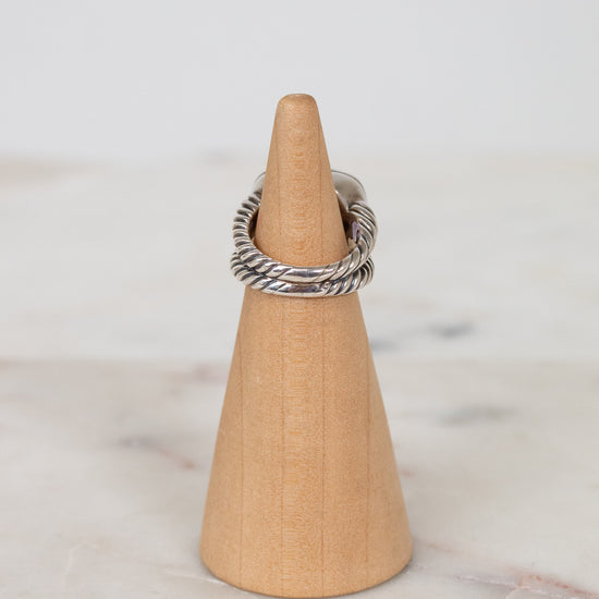 Silver ring on a wooden cone against a marble background