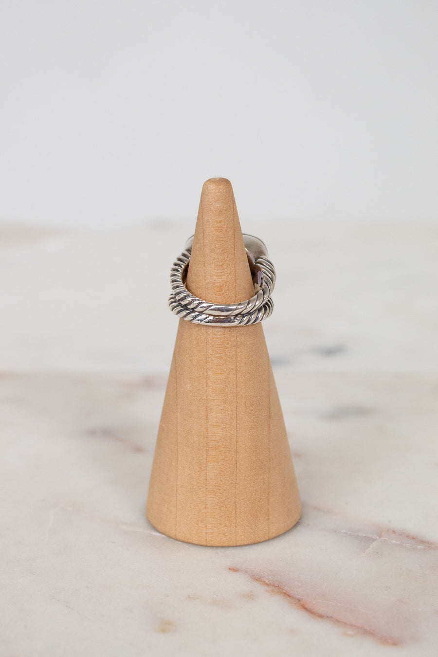 Silver ring on a wooden cone against a marble background