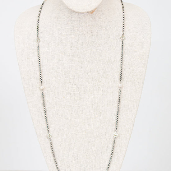 Long silver necklace on a mannequin bust against a white background