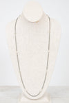 Long silver necklace on a mannequin bust against a white background
