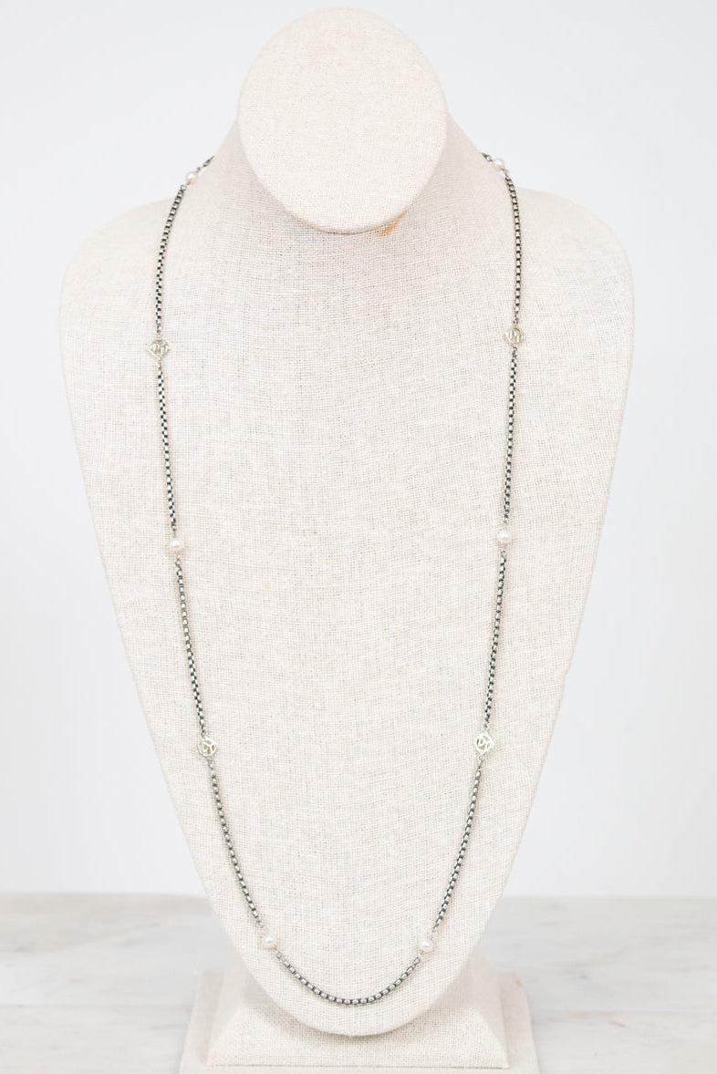 Long silver necklace on a mannequin bust against a white background