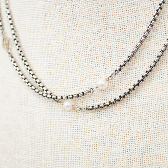 Silver necklace with pearls on a textured beige surface
