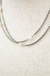 Silver necklace with pearls on a textured beige surface