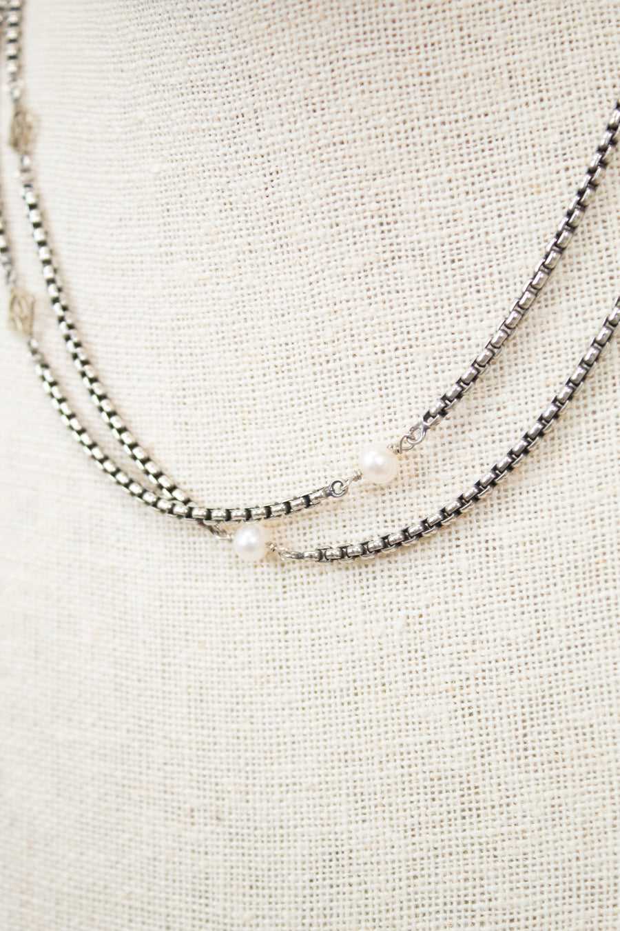 Silver necklace with pearls on a textured beige surface