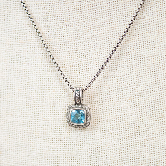 Necklace with a blue gemstone pendant on a light fabric background