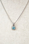 Necklace with a blue gemstone pendant on a light fabric background
