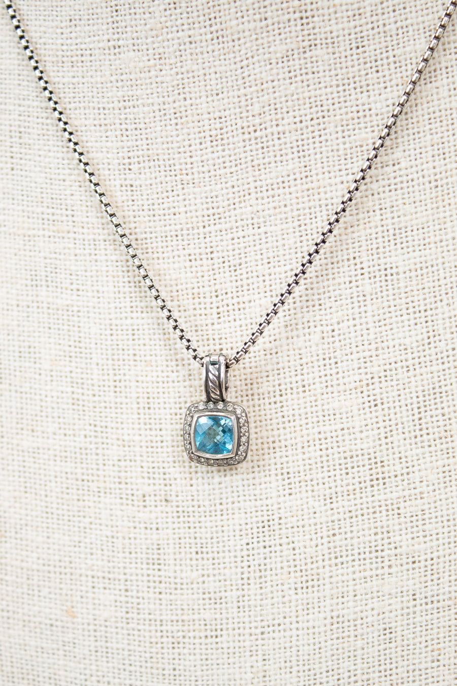 Necklace with a blue gemstone pendant on a light fabric background