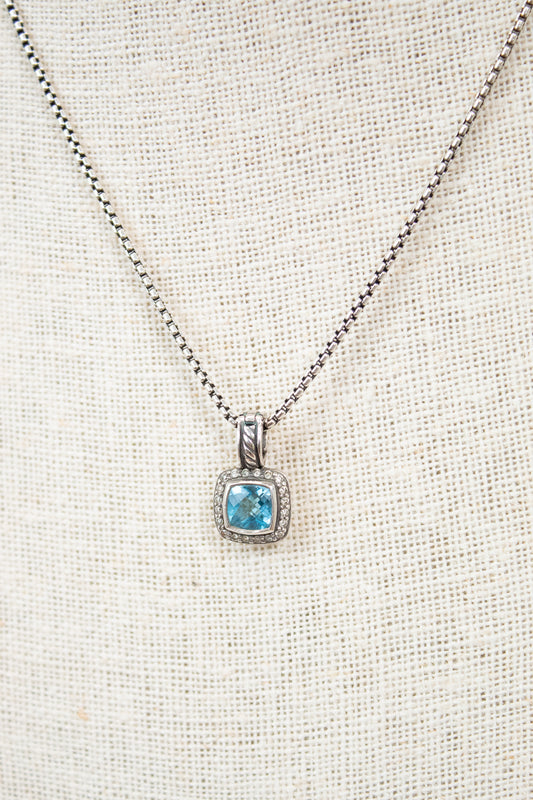 Necklace with a blue gemstone pendant on a light fabric background