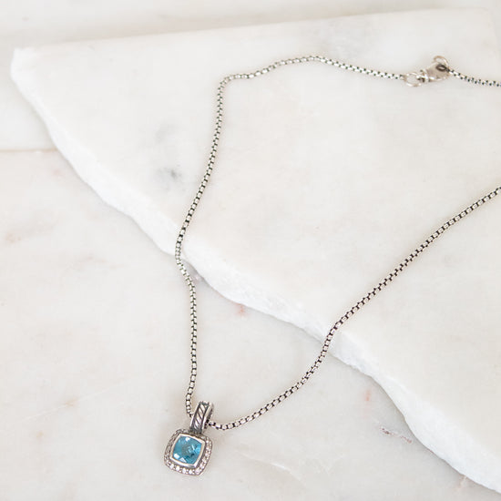 Necklace with a blue gemstone pendant on a marble surface