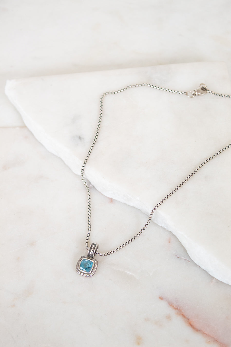 Necklace with a blue gemstone pendant on a marble surface