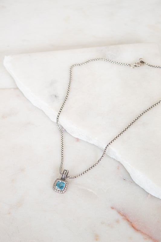Necklace with a blue gemstone pendant on a marble surface