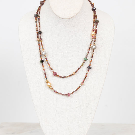 Autumnal tone beaded layered necklace displayed on a bust and against a plain background