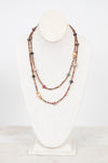 Autumnal tone beaded layered necklace displayed on a bust and against a plain background