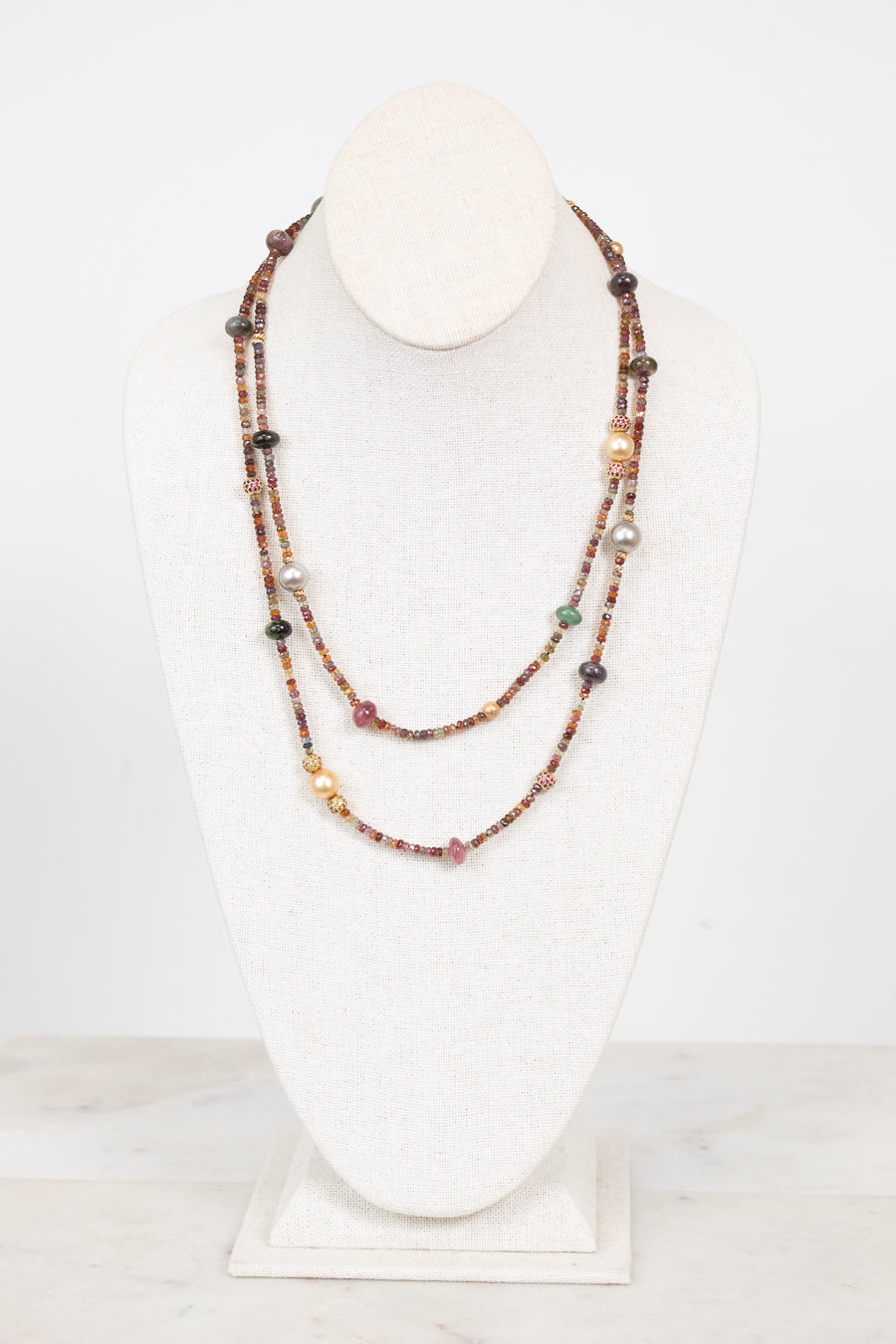Autumnal tone beaded layered necklace displayed on a bust and against a plain background