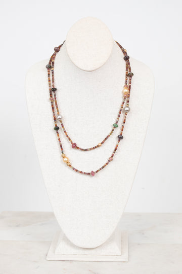 Autumnal tone beaded layered necklace displayed on a bust and against a plain background
