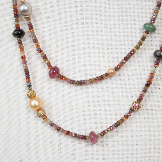 Close-up of layered necklace with autumnal colored multi-sized beads against a plain background